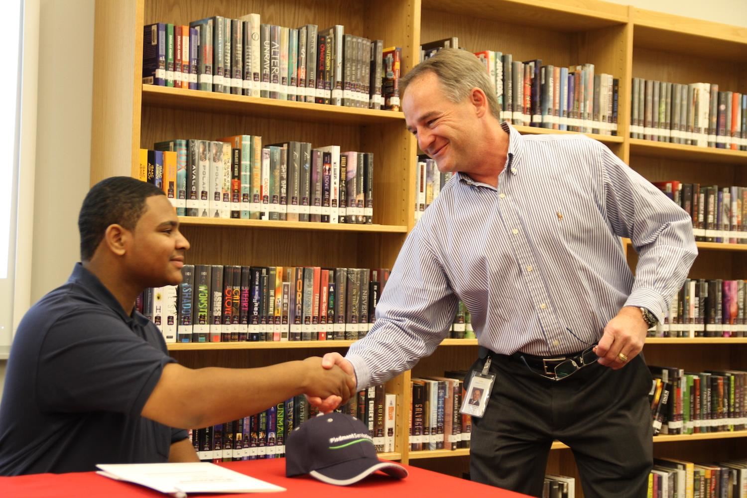 Jerry Spaulding of Piedmont Service Group shakes hands with new hire and Vernon Malone graduate Jordan Mavins. 